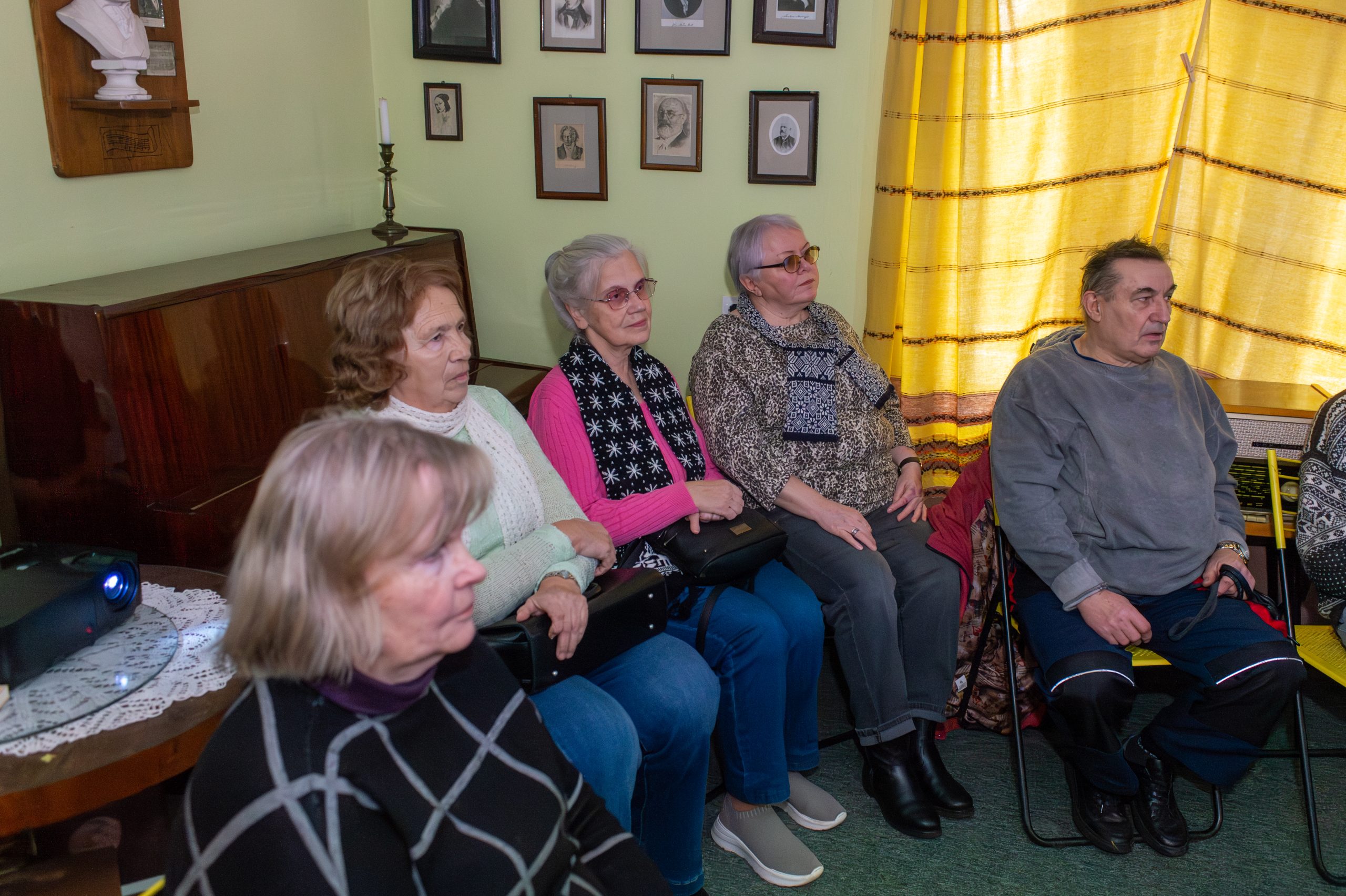 Rakstnieka Herberta Dorbes muzeja pasākumā dažāda vecuma cilvēki sēž un skatās kinožurnāla "Padomju Latvija" fragmentus