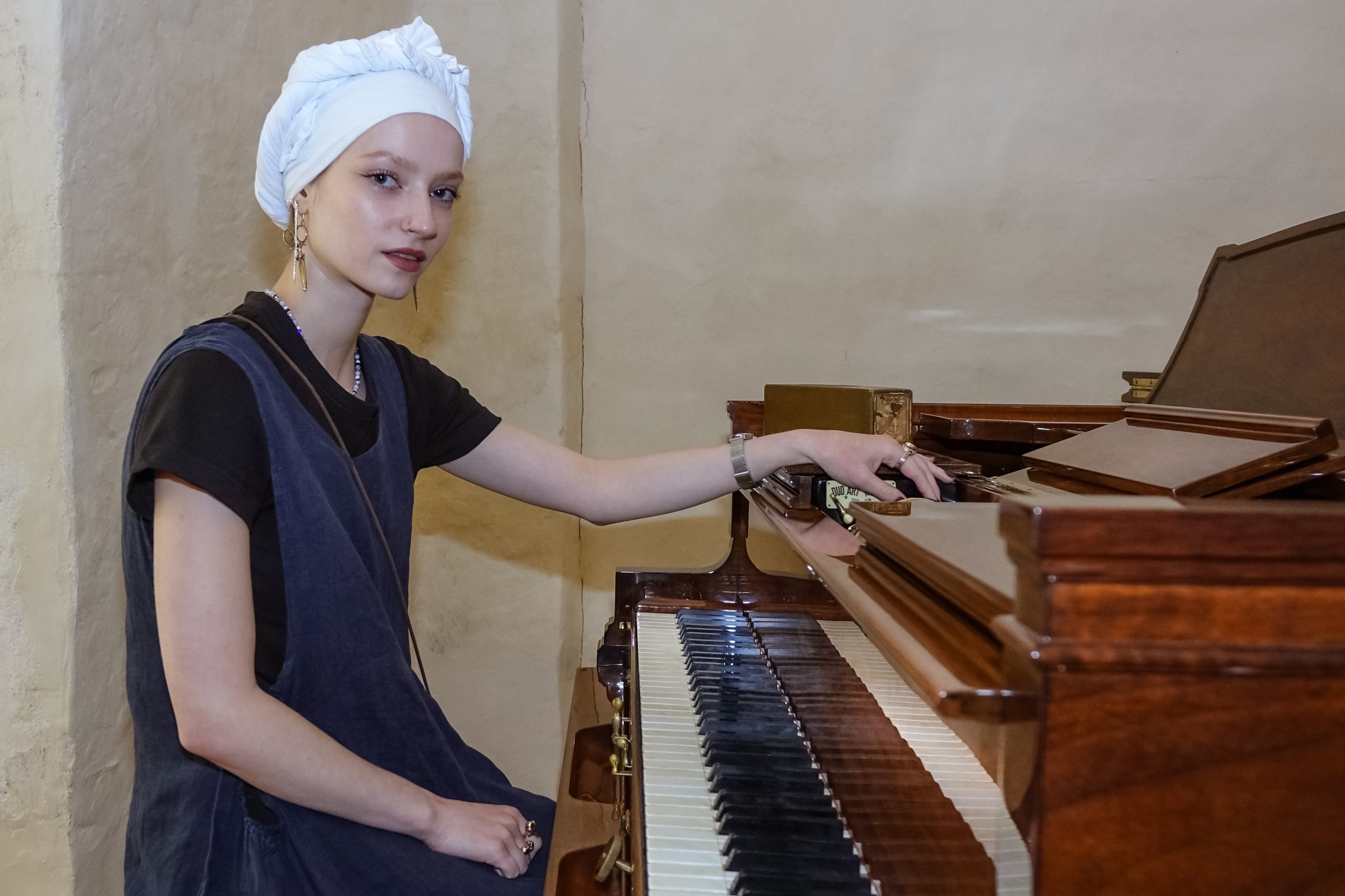 Muzeja darbiniece senatnīgā tērpā Livonijas ordeņa pils kapelā pozē pie Stenway pianolas.